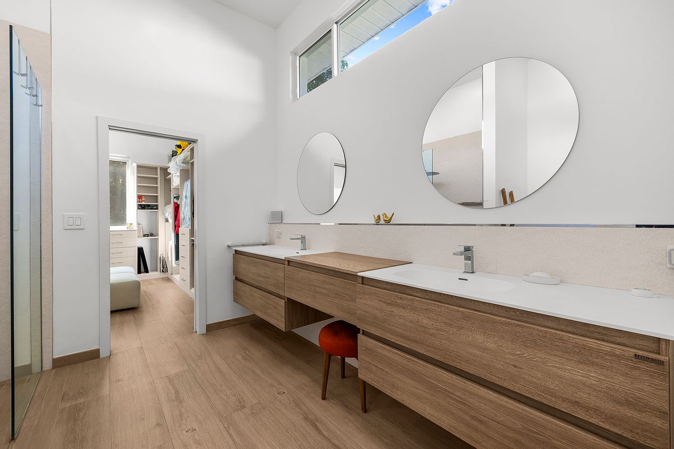 Modern master bathroom with floating walnut vanity and walk-in closet